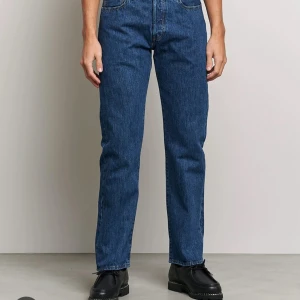 Levi's 501 blå jeans straight fit - Klassiska blå Levi's 501 jeans med rak passform och normal midja. Jeansen är tillverkade i slitstarkt denim och har fem fickor samt knappgylf. Perfekta för en clean och tidlös look. 