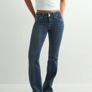 Blå bootcut jeans från Nelly - Snygga blå low waisted bootcut jeans från Nelly. Jeansen har dubbla knappar i midjan, markerade sömmar och broderade bakfickor. I nyskick! Slutsålda på nätsidan, kostar som nya 69,99€