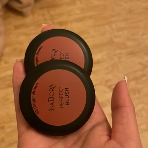 Isadora Perfect Blush Ginger Brown - Två stycken Isadora Perfect Blush i färgen 03 Ginger Brown. Rougen har en varm brun-rosa ton och kommer i rund svart dosa med spegel i locket. Innehåller 4,5g per dosa. ena har testast 2-3 ggr och den andra är oanvänd. 