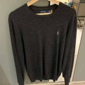 Mörkgrå merinoullströja Polo Ralph Lauren - Mörkgrå långärmad tröja från Polo Ralph Lauren i tvättbar merinoull. Medium i slim fit, sparsamt använd, nypris ca 2500.