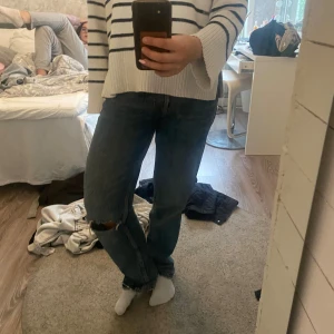 Blå baggy jeans från Zara, strl 36 - Säljer ett par blå jeans från Zara i storlek 36. Byxorna är Lågmidjade. Modellen är rak/baggy med normal passform och har en snygg sliten detalj med hål på ena knät. Jeansen har klassisk femficksdesign och är tillverkade i jeansmaterial med en mörk tvätt.