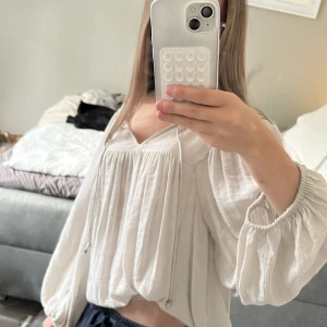 Vit blus med ballongärmar från Lindex - Säljer en luftig vit blus från Lindex i storlek M. Blusen har v-ringning, knytband framtill och ballongärmar 💗