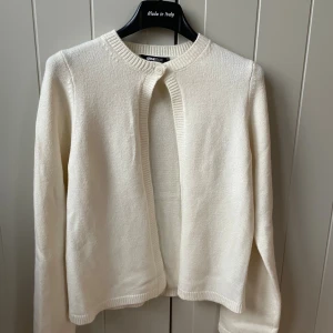 Vit kofta från Gina Tricot XS - Klassisk vit kofta från Gina Tricot i storlek XS. Modellen har rund halsringning, ribbade muddar och stängs med en enkel knapp upptill. Mjuk och stickad känsla, perfekt att slänga över en topp när det blir kyligt.