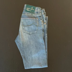 Limited edition Jacob Cohën jeans - Snygga blå jeans från Jacob Cohën med klassisk femficksdesign och unikt grönt patch på bakfickan. Jeansen har raka ben, diskret slitning och kontrastsömmar. Tillverkade i mjukt denim för en bekväm känsla och stilren look. (Dem blev ljusblåa på bild men ser ut som vanligt blått i verkligheten) Dem säljs inte längre men när dem såldes såldes dem för upp mot 5000kr