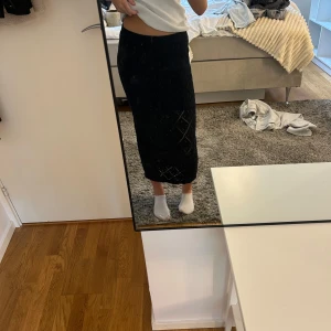 Svart långkjol med stickat mönster - Säljer en svart långkjol med snyggt stickat rutmönster. Kjolen är figurnära och har en mjuk, stickad känsla som gör den bekväm att bära. Perfekt för dig som gillar stilrena plagg med lite extra detalj. Passar till sneakers eller boots.