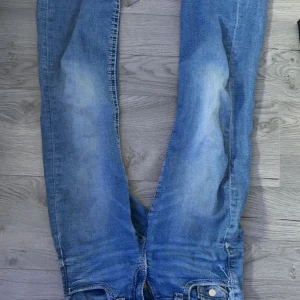 Blå jeans från Gina Tricot, storlek 152 - Snygga blå jeans från Gina Tricot i storlek 152. Jeansen har klassisk femficksdesign, raka ben och en ljus tvätt med slitningar på låren. Perfekta för dig som gillar en avslappnad och tidlös look.