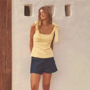 Gul linnetopp med knytband - Snygg ljusgul linnetopp med breda axelband som knyts i rosetter på axlarna. Jätte fin o bra skick säljer då den tyvär inte sitter som jag vill