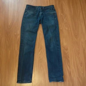 Levi's 511 blå jeans straight fit - Säljer ett par klassiska Levi's 511 jeans i mörkblå tvätt. Modellen har raka ben, fem fickor och snygga kontrastsömmar. Ikonisk Levi's patch bak och röd etikett på bakfickan. Perfekta för dig som gillar en clean och tidlös look.