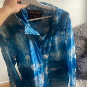 Blå och vit vindjacka från Woolrich - Säljer min windbreaker från woolrich då den är lite för stor den är i storlek xl men passar även L. Den är i bra skick och nypris brukar ligga på runt 5000-6000. Skriv om ni vill ha fler bilder och pris går att diskutera