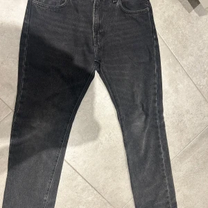 Levi's 551Z svarta jeans W28 L32 - Svarta Levi's 551Z jeans med klassisk femficksdesign och raka ben. Jeansen har hög midja och är tillverkade i slitstarkt denim. Snyggt tvättad svart färg med vintagekänsla och ikonisk läderpatch bak i midjan. Några centimeter ner syd så passar L30 också 