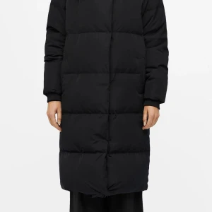 Svart lång pufferjacka med dragkedja - Säljer en svart lång pufferjacka med quiltad design och dragkedja framtill. Jackan har långa ärmar, hög krage och två sidofickor. Perfekt för kalla dagar när du vill hålla dig varm och ändå se stilren ut. Från object. Kan skicka mer bilder privat!