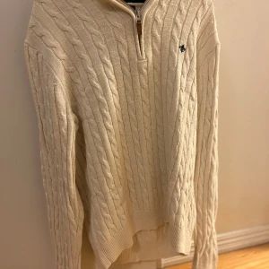 Beige cardigan från Morris - Snygg Cardigan från Morris med halv dragkedja och liten broderad logga på bröstet. Tröjan har lång ärm, ribbade muddar och klassisk kabelmönster. Pris kan diskuteras 😃