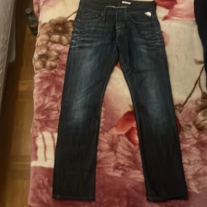 Replay mörkblå jeans straight fit - Säljer ett par mörkblå jeans från Replay med klassisk femficksdesign och snygga slitningar. Jeansen har raka ben och tydliga kontrastsömmar. Metallmärke på fickan och Replay-patch bak i midjan. Perfekta för dig som gillar en tidlös look.
