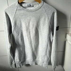Stone Island sweater - Stone Island i klassisk grått, 100 % äkta. För att bevisa äktheten finns en QR-kod på en av bilderna. QR-koden är dock täckt i annonsen för att förhindra att den blir ogiltig om flera skannar den. Skicka ett meddelande om du är intresserad, så skickar jag koden direkt till dig! Detaljer: • Marke: Stone Island • Färg: grått • Storlek: passar som S • Skick: 7/10 • Material: Bekvamt och slitstarkt tyg Tröjans ikoniska Stone Island-kompasslogotyp på vänster ärm gör den igenkännbar och ger en exklusi