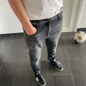 Tiger of sweden jeans - Säljer ett par svarta jeans från Tiger of sweden i modellen Pistolero. Jeansen har en snygg tvättad look med ljusare partier och klassisk femficksdesign. De är raka i modellen och har normal passform. Perfekta för dig som gillar stilrena och bekväma jeans.