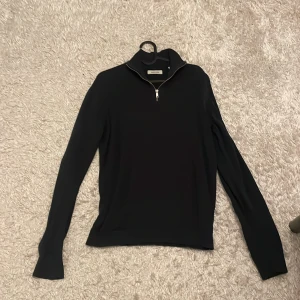 Svart half zip tröja Jack & Jones - Svart långärmad tröja från Jack & Jones med snygg half zip-dragkedja i halsen. Tröjan har en stilren design och är tillverkad i ett mjukt material som känns skönt mot huden. Perfekt för lager-på-lager och funkar året runt.