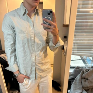 These Glory Days skjorta  - Stilren skjorta från These Glory Days i klassisk modell med bröstficka och knappar hela vägen. Skjortan har lång ärm, button down-krage och är tillverkad i mjuk bomull. Perfekt för dig som gillar en clean och enkel look.