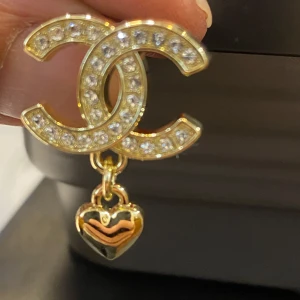  örhängen med hjärthänge -  örhängen i guldton med gnistrande stenar på och ett hängande hjärta. Superfina detaljer och lyxig känsla, perfekta för att lyfta vilken look som helst.