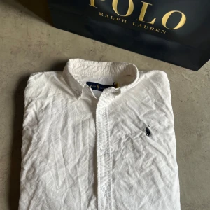 Vit skjorta från Polo Ralph Lauren - Klassisk vit skjorta från Polo Ralph Lauren med broderad marinblå logga på bröstet.Tillverkad i mjuk bomull och passar perfekt till en clean och stilren look.
