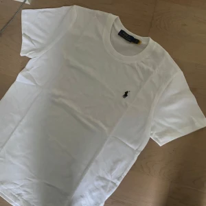 Vit t-shirt från Polo Ralph Lauren - Vit klassisk t-shirt från Polo Ralph Lauren med rund hals och broderad logga på bröstet. Tillverkad i mjuk bomull och har en normal passform. Perfekt basic-plagg med stilren look.