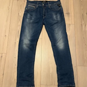 Replay Grover Hyperflex jeans blå - Snygga Replay Grover Hyperflex jeans i klassisk blå tvätt med lätt slitna detaljer och raka ben. Jeansen har normal passform, fem fickor och coola sömmar på bakfickorna. Perfekt stretch tack vare Hyperflex-materialet för extra komfort storleken är 31/32. Dessa är använda bara några få gånger så inga skador. Hör av er vid frågor.