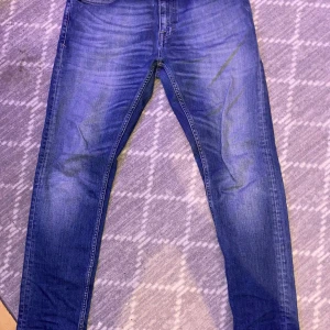 Blå jeans från Tiger of Sweden - Snygga blå jeans från Tiger of Sweden med klassisk femficksdesign och ljusa slitningar framtill. Modellen är skinny, men sitter in tight men luftigt . Jeansen har normal midja och är tillverkade i mjukt denimtyg med snygga detaljer på bakfickorna. Samt och den lite fade också🤟🏽🤟🏽🤟🏽