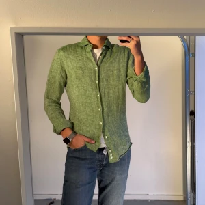 Grön linneskjorta La Chemise L - Grön skjorta från La Chemise Norrmalm i storlek L med extra långa ärmar, sitter som en medium. Tillverkad i 100% premium linne och har klassisk krage, vita knappar och en avslappnad passform. Nypris 898kr. 