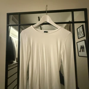 Vit långärmad tröja Gina Tricot XS - En stilren vit långärmad tröja från Gina Tricot i storlek XS. Tröjan har rund halsringning och är gjord i mjukt, stretchigt material som sitter skönt mot kroppen. Perfekt att matcha med jeans eller kjol för en clean look.