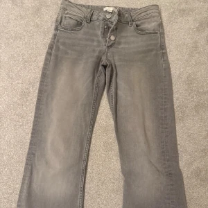 Grå jeans från Gina Tricot, storlek 158 - Snygga grå jeans från Gina Tricot. Med klassisk femficksdesign och tre silverfärgade knappar i midjan. Jeansen har en straight passform och är tillverkade i mjukt jeanstyg som ger en cool och avslappnad vibe.
