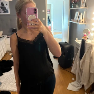 Svart linne med spets från JDY - Svart linne från JDY i storlek 36 med tunna axelband och snygg spetsdetalj längs v-ringningen. 