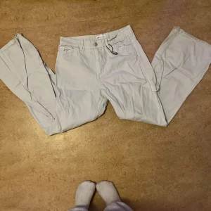 Ljusblå cargopants från Zara - Säljer ett par ljusgrå cargopants från Zara med raka ben och klassiska cargofickor på sidorna. Har liten blå fläck på fikan 
