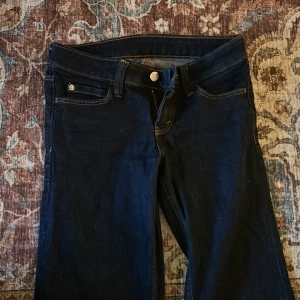 Bootcut jeans från Cheap Monday - Mörkblå bootcut jeans från Cheap Monday med klassisk femficksdesign och snygga kontrastsömmar. Jeansen har normal passform och är tillverkade i jeansmaterial med dragkedja och knapp framtill. Perfekt för dig som gillar retrovibbar och breda ben. Dem är i W27 och L30