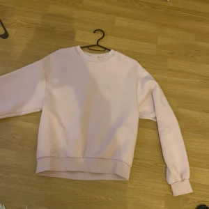 Ljusrosa sweatshirt från H&M - En enkel och snygg ljusrosa sweatshirt från H&M i storlek M. Tröjan har rund hals, ribbade muddar och är tillverkad i mjuk bomull med fleece på insidan. Perfekt för chill dagar och passar till jeans eller mjukisbyxor.