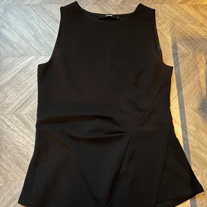 Svart ärmlös topp från Bik Bok - svart topp från Bik Bok i storlek S.  asymmetrisk drapering framtill. 