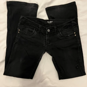 Svarta jeans från Blue Blue med pärlor - Snygga vintage y2k ultra low rise / ultra low waist svarta jeans från Blue Blue med dekorativa pärlor och broderi på bakfickorna. Modellen har fickor fram och bak med fjäril på bakfickorna. Stor storlek 40 men är 36 och de passar mig bra. Fler bilder finns. Jeansen är i en sliten modell så vissa lappar är lättare och/eller något slitna. Det finns också ett hål i vänster ben vilket inte borde påverka slitaget. 