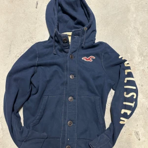 Vintage Hollister hoodie med knappar - Extremt eftertraktad och sällsynt vintage  Hollister hoodie med knappar! Grymt skick, inga defekter - ser exakt ut som på bild! Storlek M. Skriv vid frågor!💬