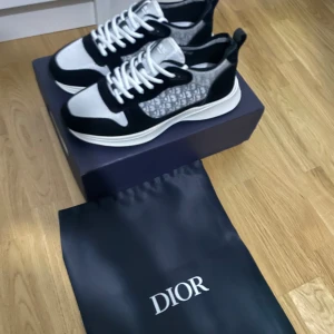 Dior B23 sneakers svart/vit monogram - Säljer ett par Dior B23 sneakers i svart och vitt med ikoniskt Dior-monogram på sidan. Skorna har mesh och mockadetaljer, vita snören och en chunky vit sula. Perfekt för dig som vill ha en lyxig och trendig sneaker med tydlig designerstil. Priset kan diskuteras!!!!!!!!