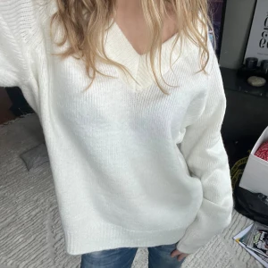Vit stickad oversized tröja - Säljer denna sjukt mysiga vita stickade tröjan med v-ringning och långa ärmar. Modellen är oversized och har breda ribbade muddar vid ärmslut och nederkant. Perfekt att slänga på sig nu under höstsäsongen, den är så enkel att styla också! Går att styla till skolan, julen men också när du bara vill ha en chilldag hemma, Enkel och stilren design som funkar till allt 🫶🏼 Inga tecken på användning!
