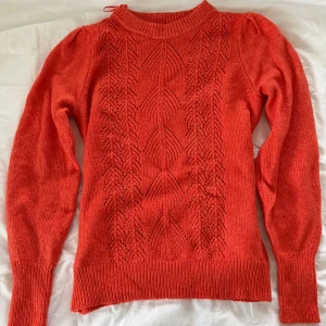 Orange stickad tröja från M&S Collection - Snygg orange stickad tröja från M&S Collection med långärmad design och coolt hålmönster framtill. Tröjan har ribbade muddar och en rund halsringning. Perfekt för dig som gillar färg och vill ha något som sticker ut lite extra. Den är i bra skick och har inga tecken på användning🥰🥰