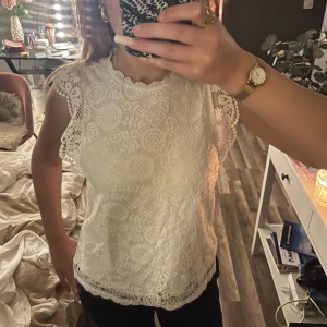 Vit spetsblus med volangärmar - Säljer en superfin vit blus i spets med detaljerade volangärmar och rund hals. Blusen har ett vackert spetsmönster med blommiga inslag och en feminin kant nedtill. Perfekt för dig som gillar romantisk och söt stil.