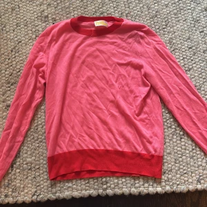 Rosa och röd ulltröja XS - Snygg rosa tröja från From Future  med röd ribbad kant vid hals och nederdel. Modellen är klassisk med rund hals och långa ärmar, perfekt för dig som gillar färg och vill ha något mjukt och skönt. Storlek XS.Superskönt material 