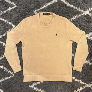 Polo Ralph Lauren tröja  - Snygg beige stickad tröja från Polo Ralph Lauren med klassisk rund hals och broderad logga på bröstet. Storlek S. Jag är 180cm, 68kg och den passar mig perfekt. 