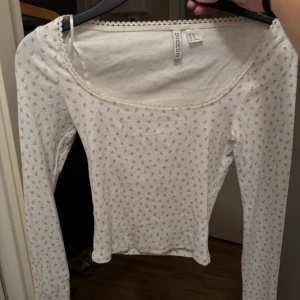 Vit blommig långärmad topp HM - Söt långärmad topp från hm vit med små ljusblå blommor. Ribbad struktur och rundad hals med spetskant. 