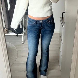 Mörkblå lowwaist bootcut jeans låg midja - SÄLJES ELLER BYTES MOT STORLEK S!! Snygga mörkblå jeans med bootcut och låg midja. Jeansen har klassisk femficksdesign, lätt slitning framtill och markerade sömmar. Perfekta för dig som gillar en retro vibe och vill ha en bekväm passform med lite utsvängda ben. Det har lite röd/lila sömmar och snygga detaljer på bakfickan, max använda en gång!! Annars helt nya. Från Gina Young 14+  