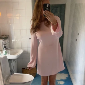 Ljusrosa kortklänning med vida ärmar - Supersöt ljusrosa klänning med långa, vida ärmar och enkel, rak passform. Klänningen är kort och har en mjuk, flowy känsla som gör den riktigt bekväm. Perfekt för dig som gillar en stilren look med en touch av sötma. Endast använd en gång🥰