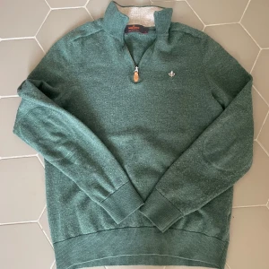 Grön merinoullströja från Morris - Snygg grön tröja från Morris i 100% merinoull med halv dragkedja och diskret logga på bröstet. Tröjan har ribbade muddar och hög krage, perfekt för lager-på-lager. Passar dig som gillar klassisk men avslappnad stil. Den är i barn large men den passar mig som har xs nu på mina kläder.