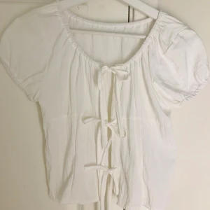 Fin vit topp - Fin vit topp med rosetter fram! Perfekt att matcha jeans eller kjol nu på hösten! 🍁