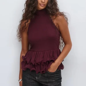 Vinröd polotopp med volang - Säljer en vinröd polotopp med ärmlös design och hög hals. Helt ny och lappen kvar!