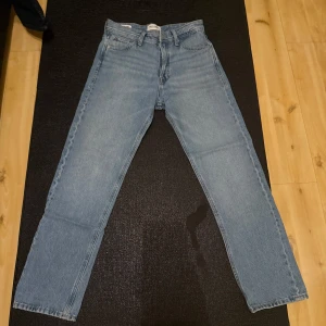 Jack & Jones Relaxed Chris ljusblå jeans - Ljusblå jeans från Jack & Jones i modellen Relaxed Chris. Klassisk femficksdesign, raka ben och avslappnad passform. Tillverkade i bomull med snygg denimlook och detaljer i silver och koppar. Perfekta för en chill och stilren vardagsoutfit.