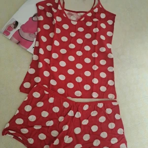 Röda prickiga shorts med linne - Säljer ett par röda shorts med vita stora prickar, matchande med ett linne i samma mönster. Shorts har elastisk midja och är gjorda i mjukt bomullsmaterial, perfekt för chill hemma. Snyggt och lekfullt set för dig som gillar färg och mönster.